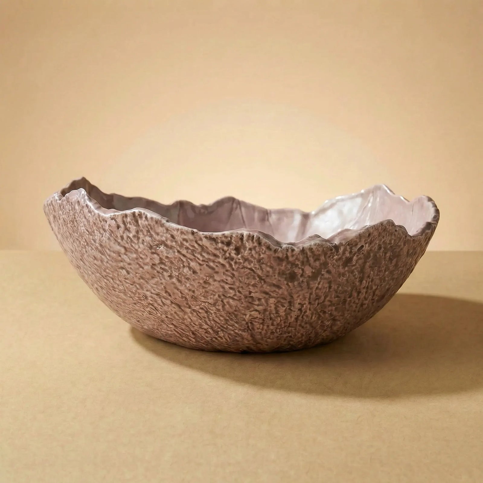 Ciotola grande in ceramica artigianale con bordo irregolare e texture materica su sfondo beige