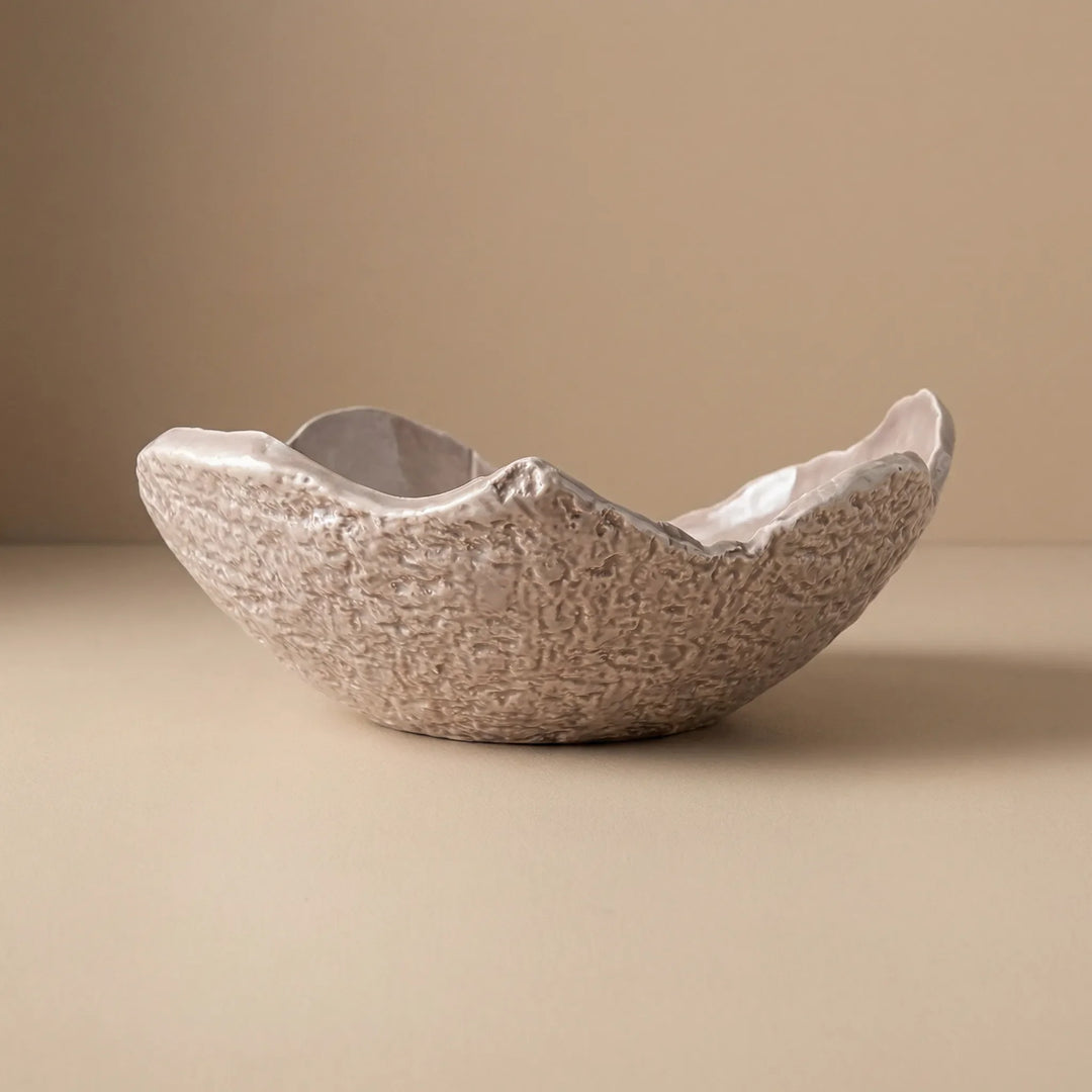 Ciotola grande in ceramica artigianale con bordo irregolare e texture naturale su sfondo beige
