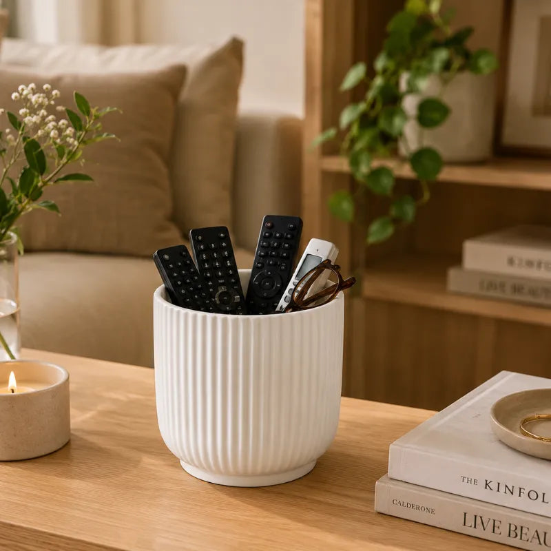 Vaso Pitti bianco rigato utilizzato come contenitore per telecomandi e occhiali su tavolino da soggiorno, ideale per organizzare piccoli oggetti con stile.