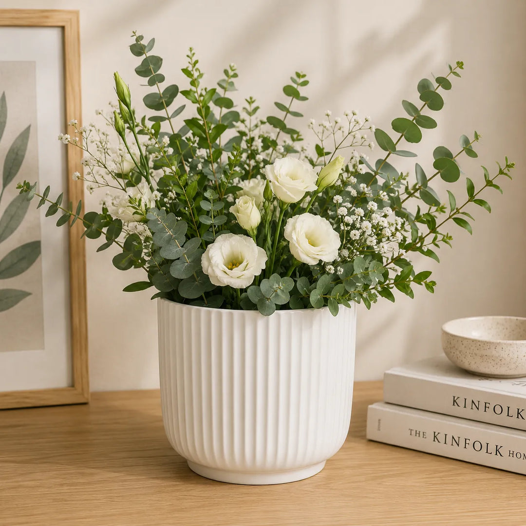 Vaso Pitti bianco rigato con elegante composizione di fiori bianchi ed eucalipto, ideale come centrotavola decorativo per soggiorno o ufficio.