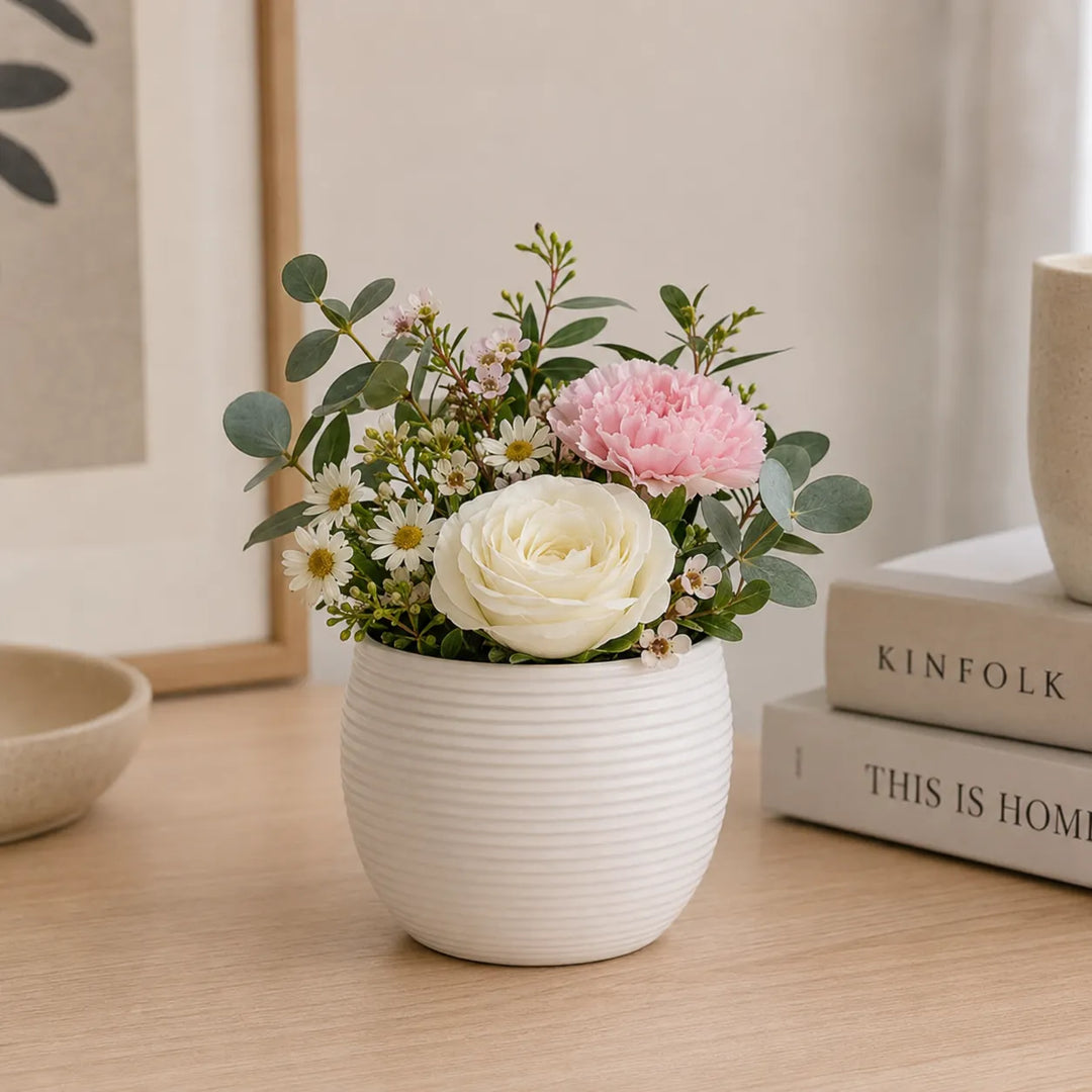 Vaso Sally bianco in ceramica con composizione floreale di rosa bianca, garofano rosa, margherite ed eucalipto, ideale come decorazione elegante per la casa.