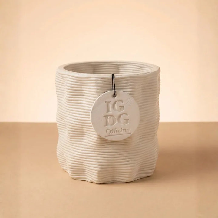 Vaso in ceramica beige con texture ondulata su sfondo neutro minimal