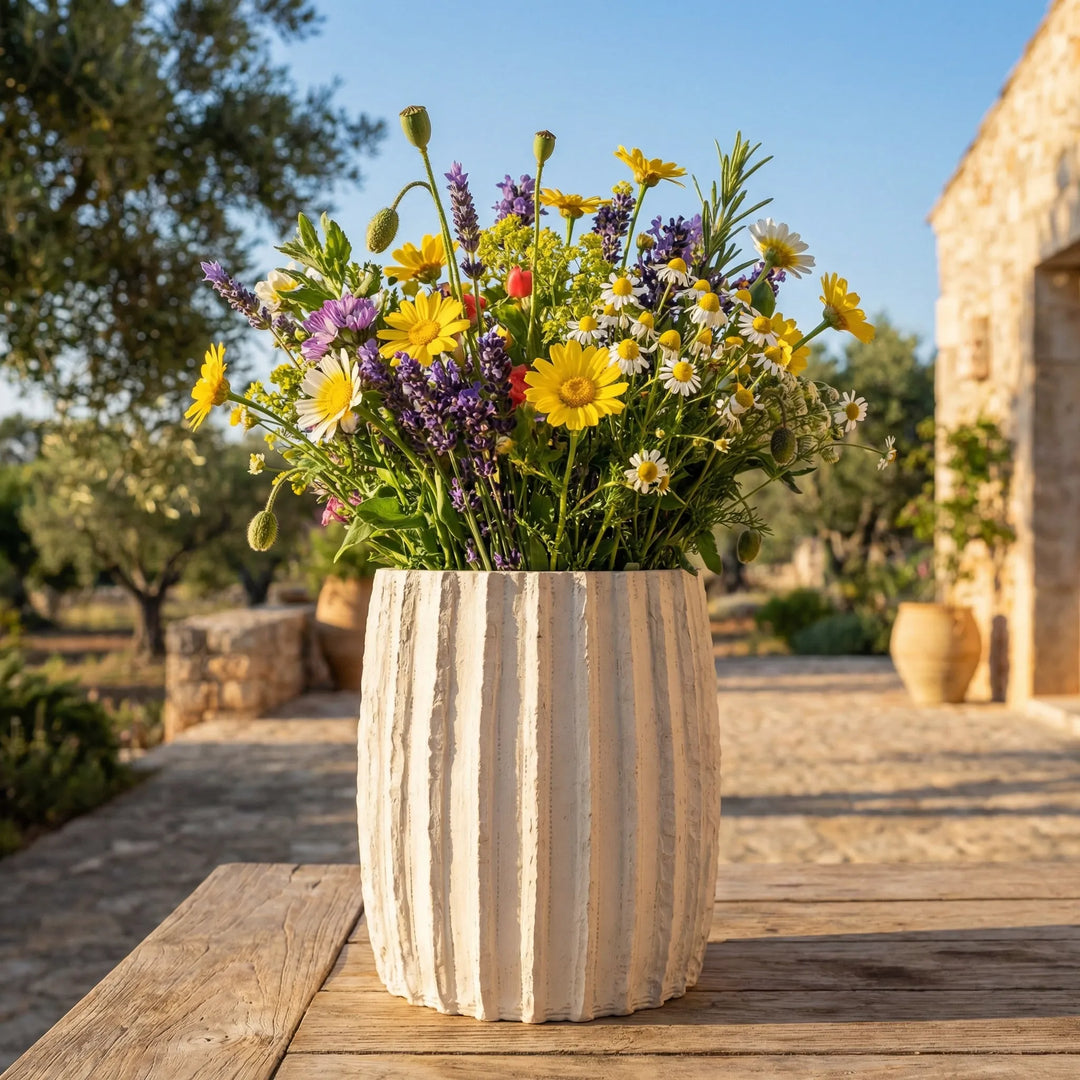 Vaso Dafne L con bouquet di fiori di campo su tavolo in legno in giardino mediterraneo