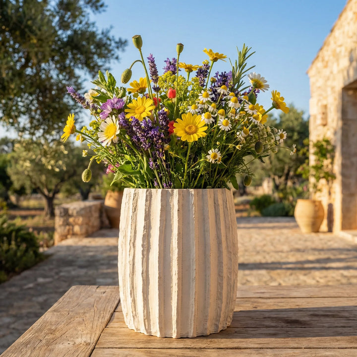 Vaso Dafne L con bouquet di fiori di campo su tavolo in legno in giardino mediterraneo